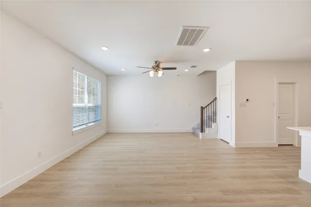 a view of empty room with wooden floor and fan