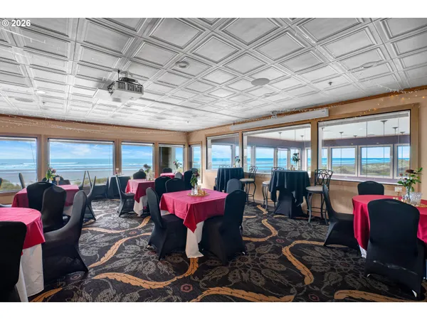 a view of a dining room with furniture large windows and kitchen view