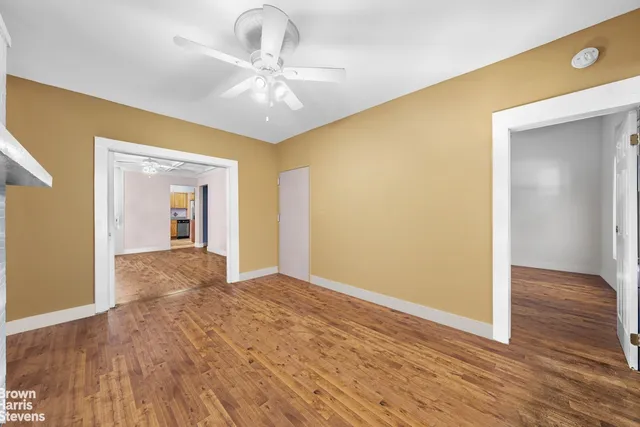 a view of an empty room with window and wooden floor