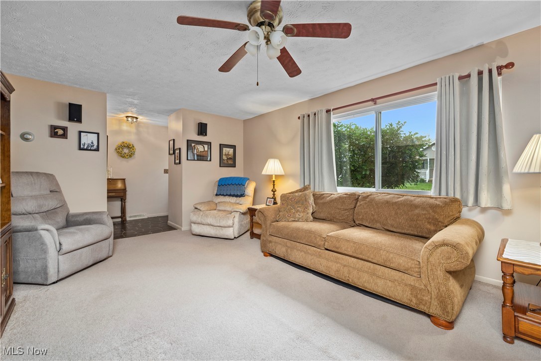 215 Sunset Road Avon Lake, OH 44012 - Photo 5 of 32 Carpeted living area with a ceiling fan, baseboards, and a textured ceiling