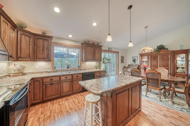 a kitchen with granite countertop a stove a sink a dining table and chairs