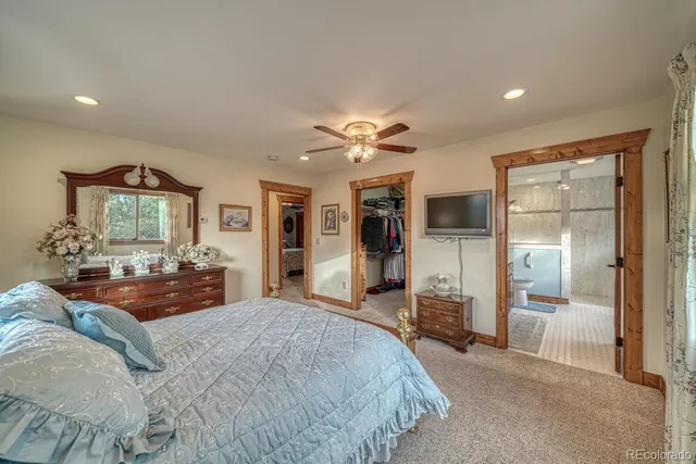 a spacious bedroom with a large bed a chandelier and mirror