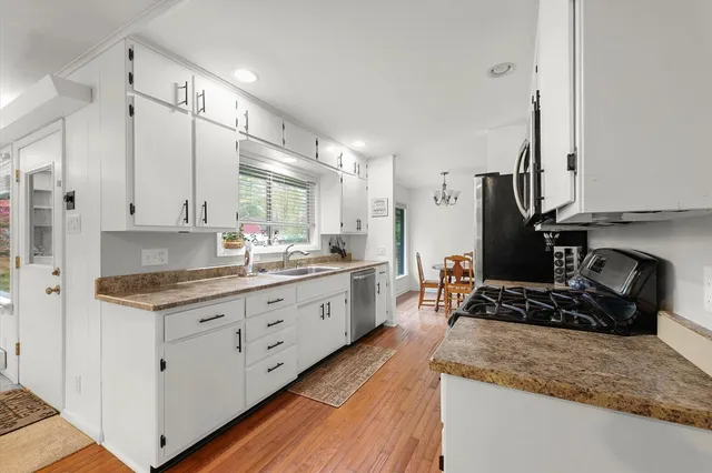 a large kitchen with stainless steel appliances granite countertop a lot of counter space and wooden floors