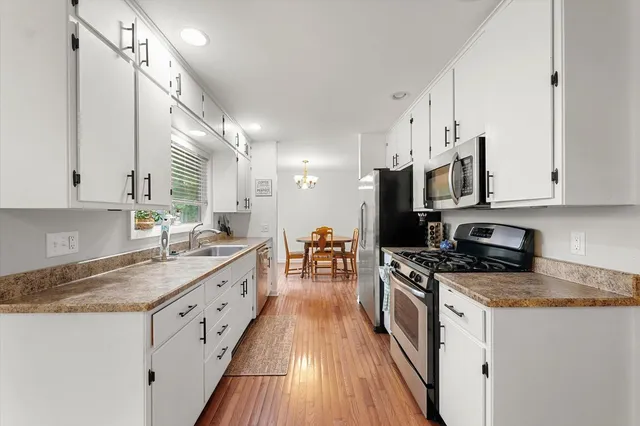 a kitchen with stainless steel appliances a stove a microwave a sink a refrigerator and chairs