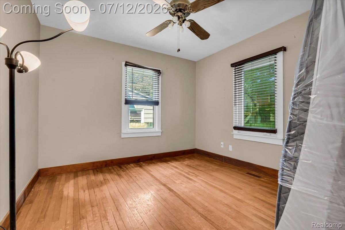 624 North Prospect Road Ypsilanti, MI 48198 - Photo 8 of 28 Room featuring wood-finish flooring, two windows with blinds, a ceiling fan, and light-toned walls