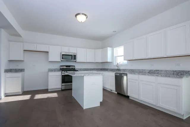 a kitchen with granite countertop white cabinets and stainless steel appliances