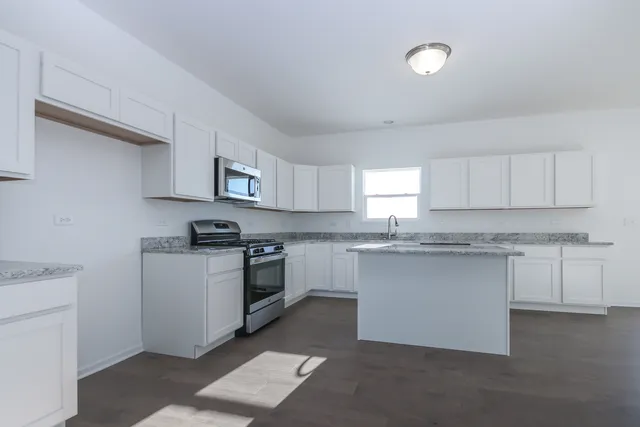 a kitchen with granite countertop white cabinets and white appliances