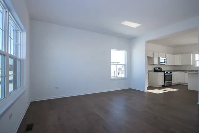 a view of empty room with kitchen and window
