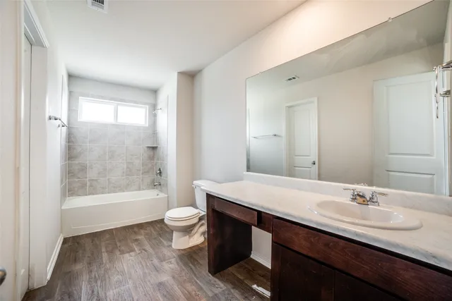 a bathroom with a granite countertop sink a toilet a mirror and bathtub