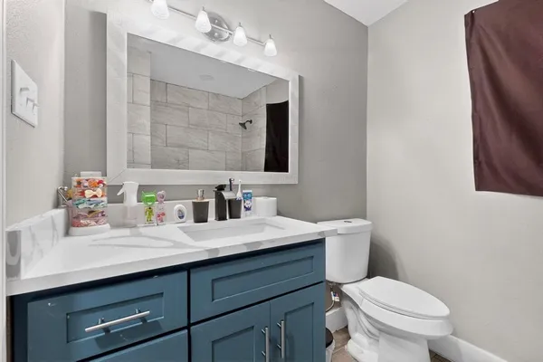 a bathroom with a granite countertop toilet sink and mirror