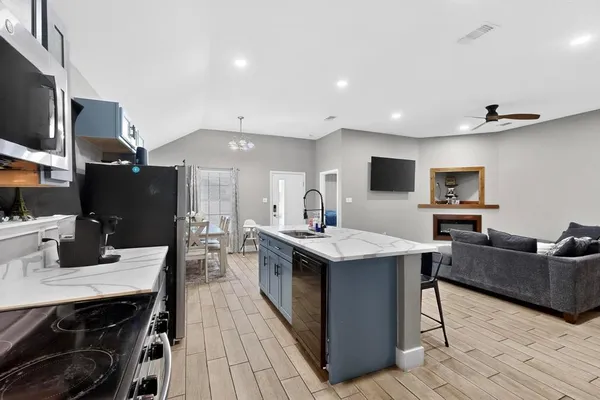 a kitchen with stainless steel appliances granite countertop a sink dishwasher a stove and a refrigerator with wooden floor