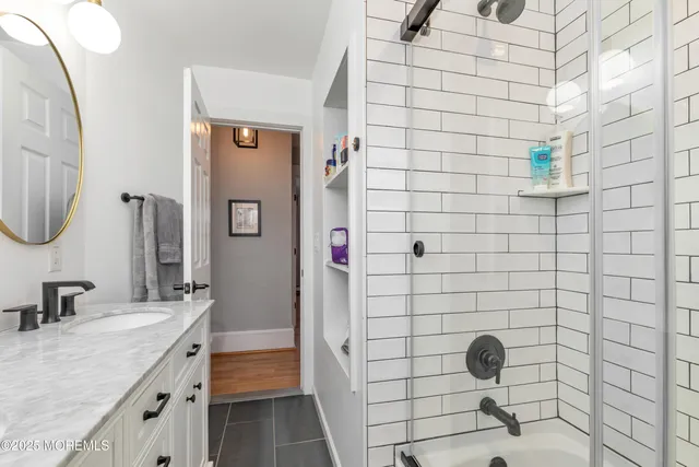 a bathroom with a granite countertop sink a toilet a mirror and shower