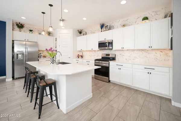 a kitchen with kitchen island a dining table chairs sink and cabinets