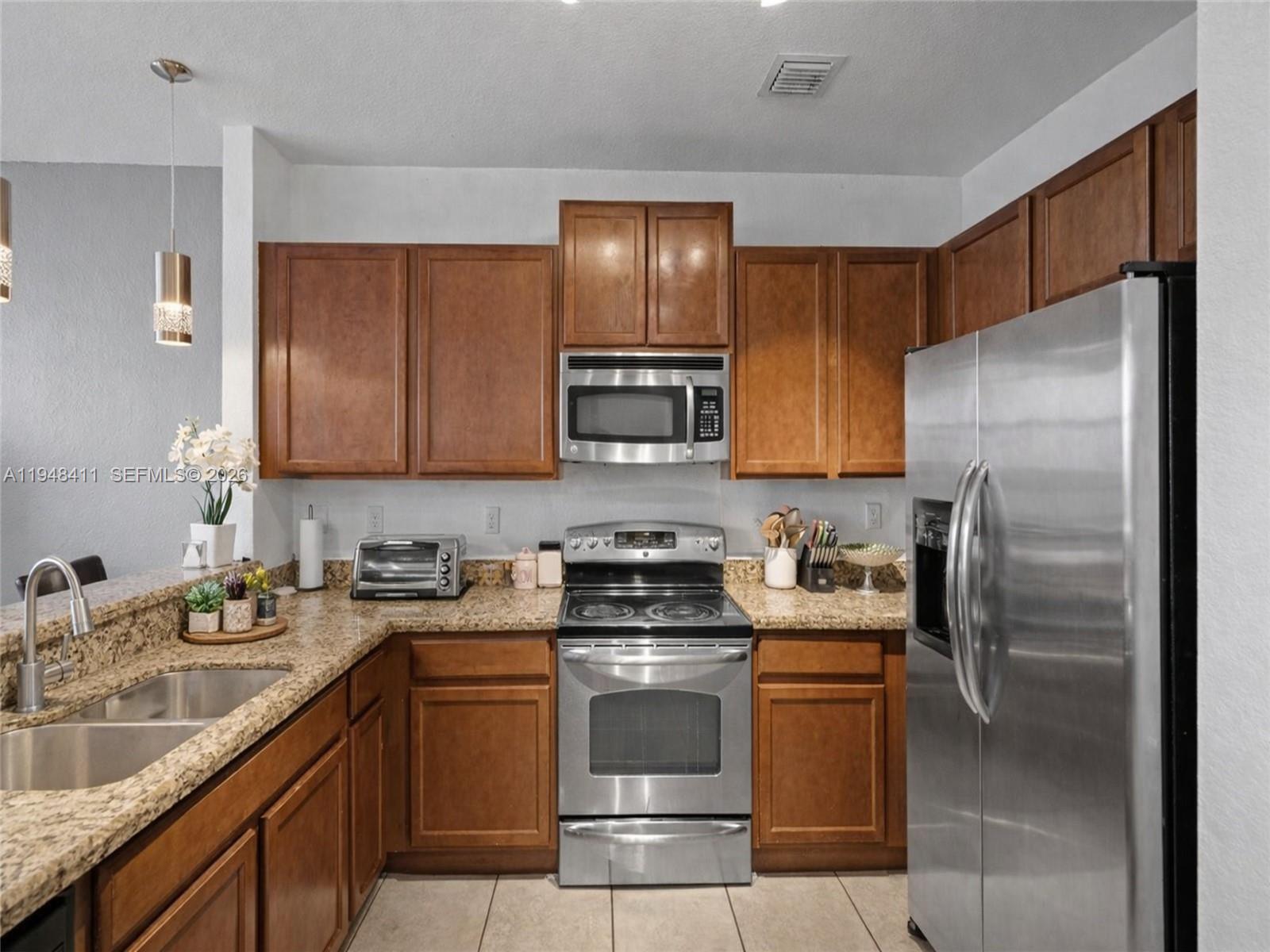 550 Northeast 33rd Terrace Homestead, FL 33033 - Photo 8 of 31 a kitchen with a sink a refrigerator and a stove top oven