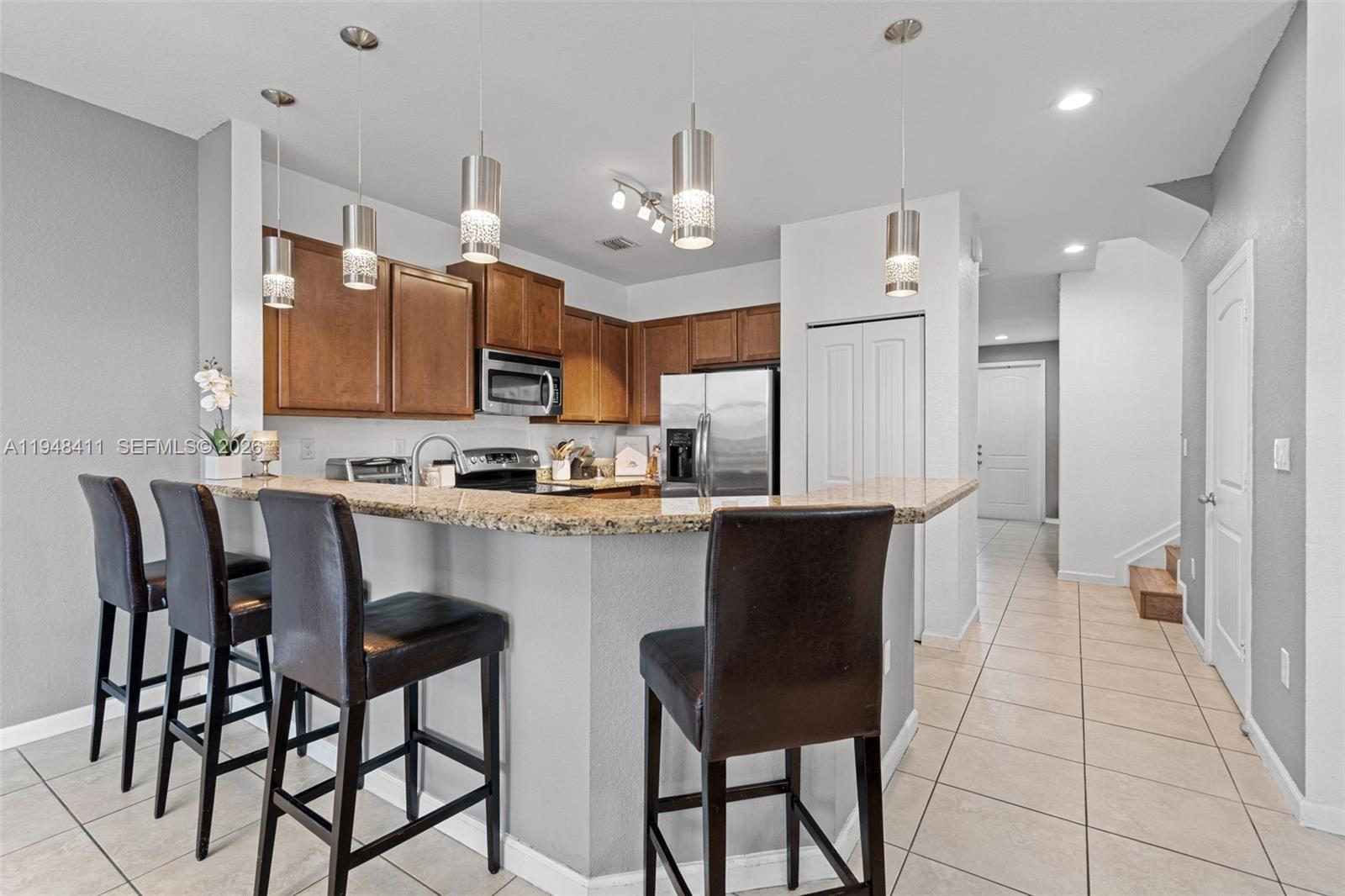 550 Northeast 33rd Terrace Homestead, FL 33033 - Photo 10 of 31 a kitchen with stainless steel appliances granite countertop a stove a refrigerator a oven a sink with a dining table and chairs