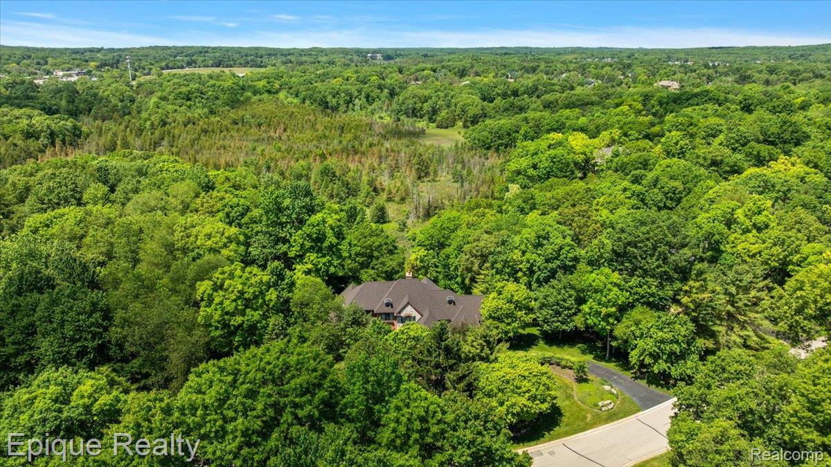 7662 Devins Ridge Clarkston, MI 48348 - Photo 22 of 81 Elevated property featuring a dark-tiled roof and extensive surrounding tree canopy