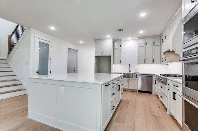 a large kitchen with stainless steel appliances granite countertop a lot of counter space and wooden floors