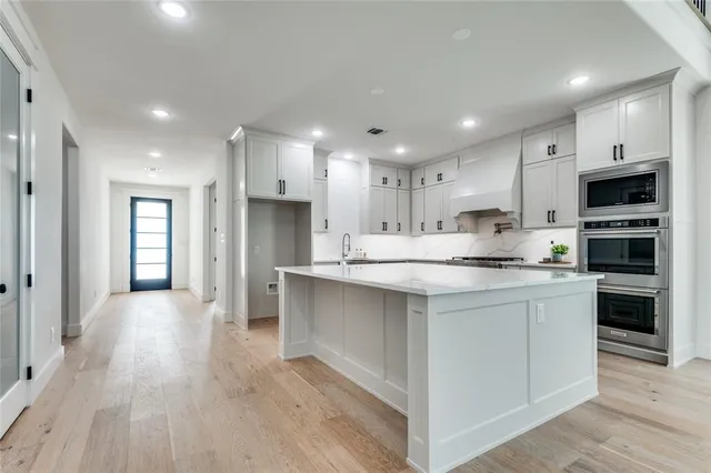 a kitchen with stainless steel appliances kitchen island granite countertop a stove top oven a sink and a refrigerator