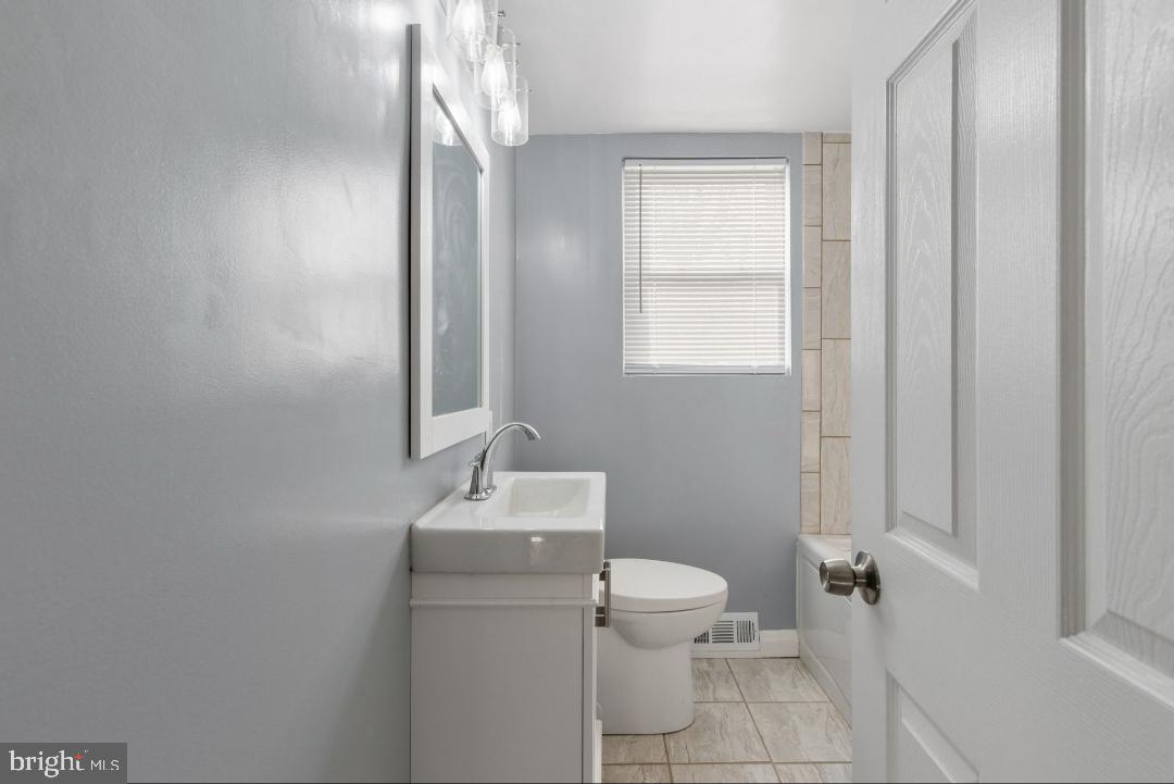 5102 Plymouth Road Baltimore, MD 21214 - Photo 17 of 32 a bathroom with a toilet a sink and mirror