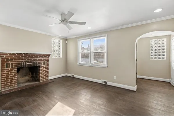 an empty room with windows a fireplace a ceiling fan and wooden floor