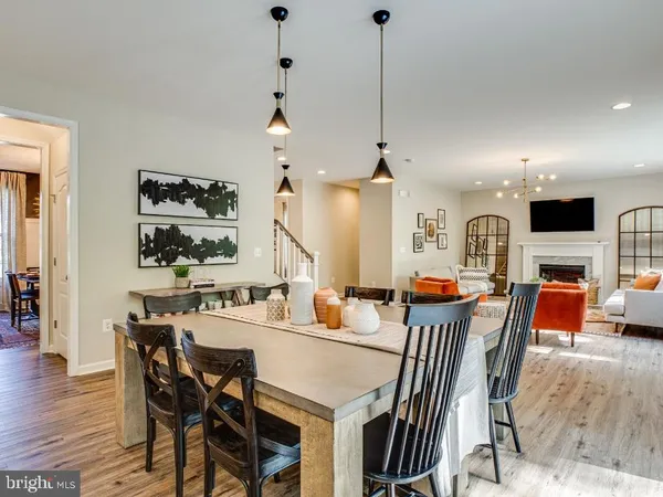 a view of a dining room and livingroom with furniture wooden floor a rug a fireplace and a chandelier