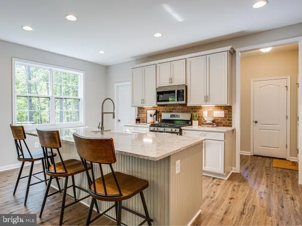 a kitchen with stainless steel appliances granite countertop a stove top oven a sink dishwasher and a refrigerator with wooden floor