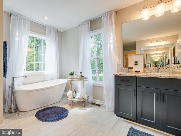 a spacious bathroom with a tub sink and mirror
