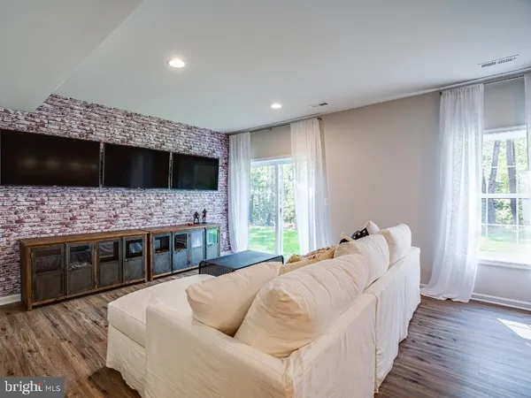 a living room with stainless steel appliances furniture a flat screen tv and a fireplace