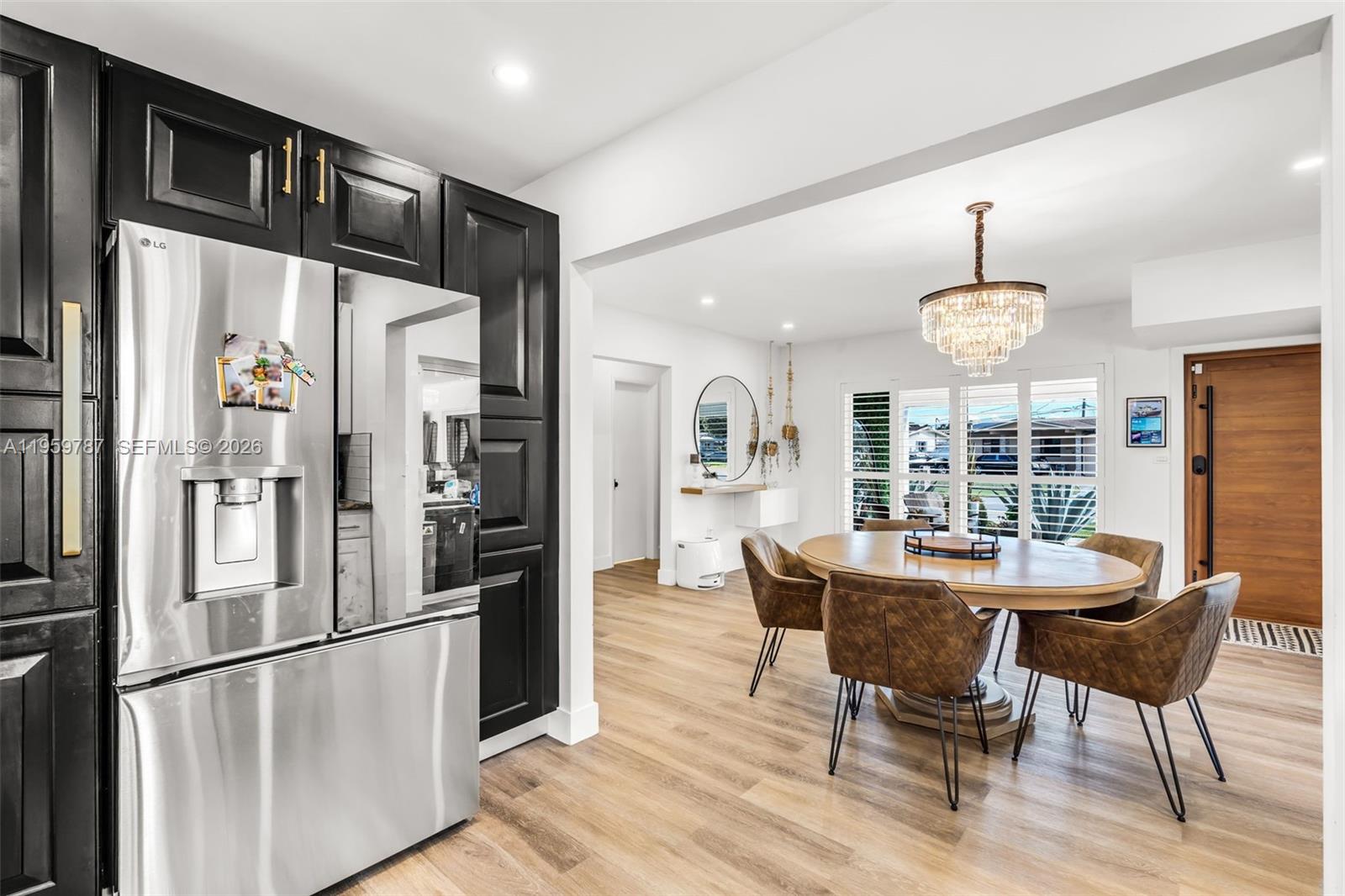 10971 Southwest 177th Street Miami, FL 33157 - Photo 9 of 41 a kitchen with stainless steel appliances a refrigerator a stove a dining table and chairs with wooden floor
