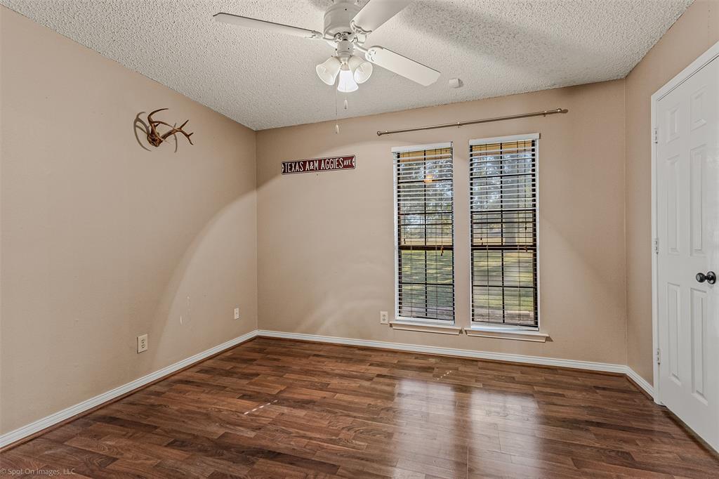 9510 South State Highway Scurry, TX 75158 - Photo 11 of 26 an empty room with wooden floor chandelier fan and windows