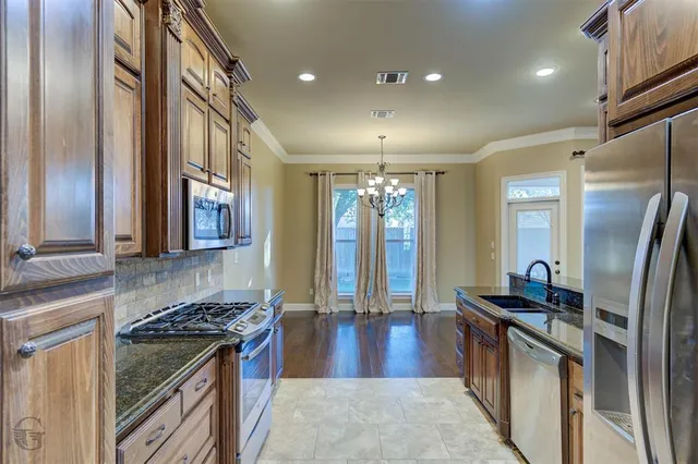 a kitchen with stainless steel appliances granite countertop a stove a sink and a refrigerator