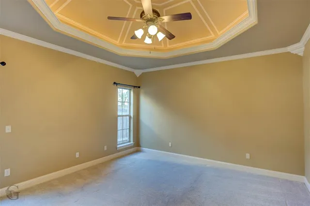 an empty room with a chandelier fan and windows