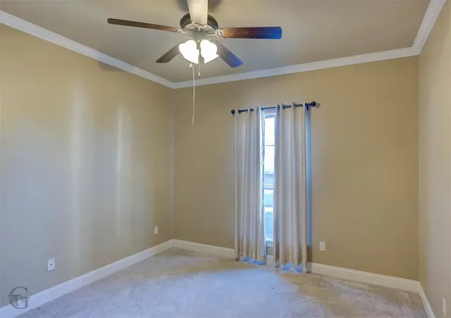 an empty room with a chandelier fan and windows