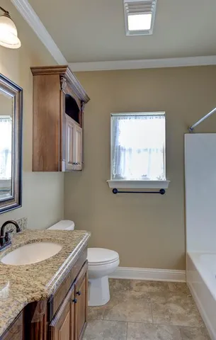 a bathroom with a granite countertop sink and a toilet