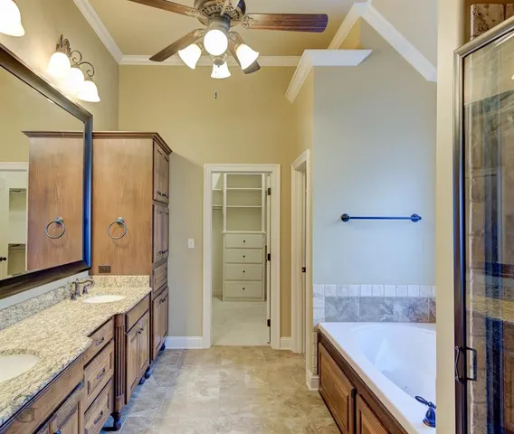 a bathroom with a granite countertop double vanity sink a mirror and a shower