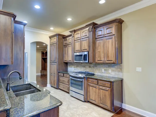 a kitchen with stainless steel appliances granite countertop a sink stove and refrigerator