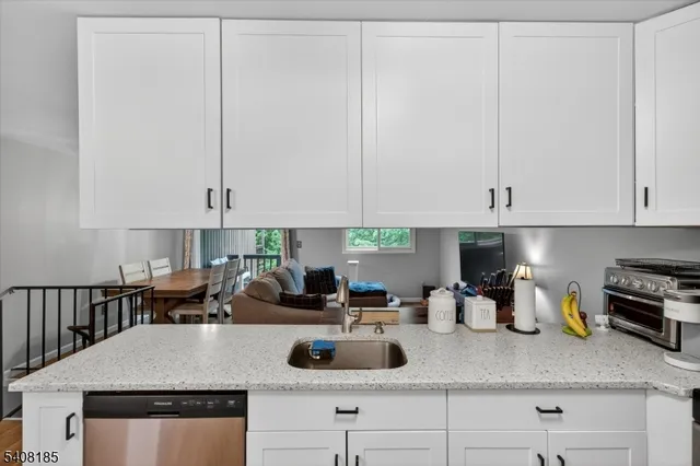 a kitchen with kitchen island granite countertop a sink a stove and white cabinets