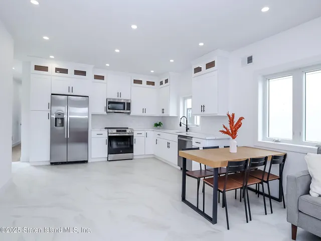 a kitchen with stainless steel appliances granite countertop a sink a stove and white cabinets
