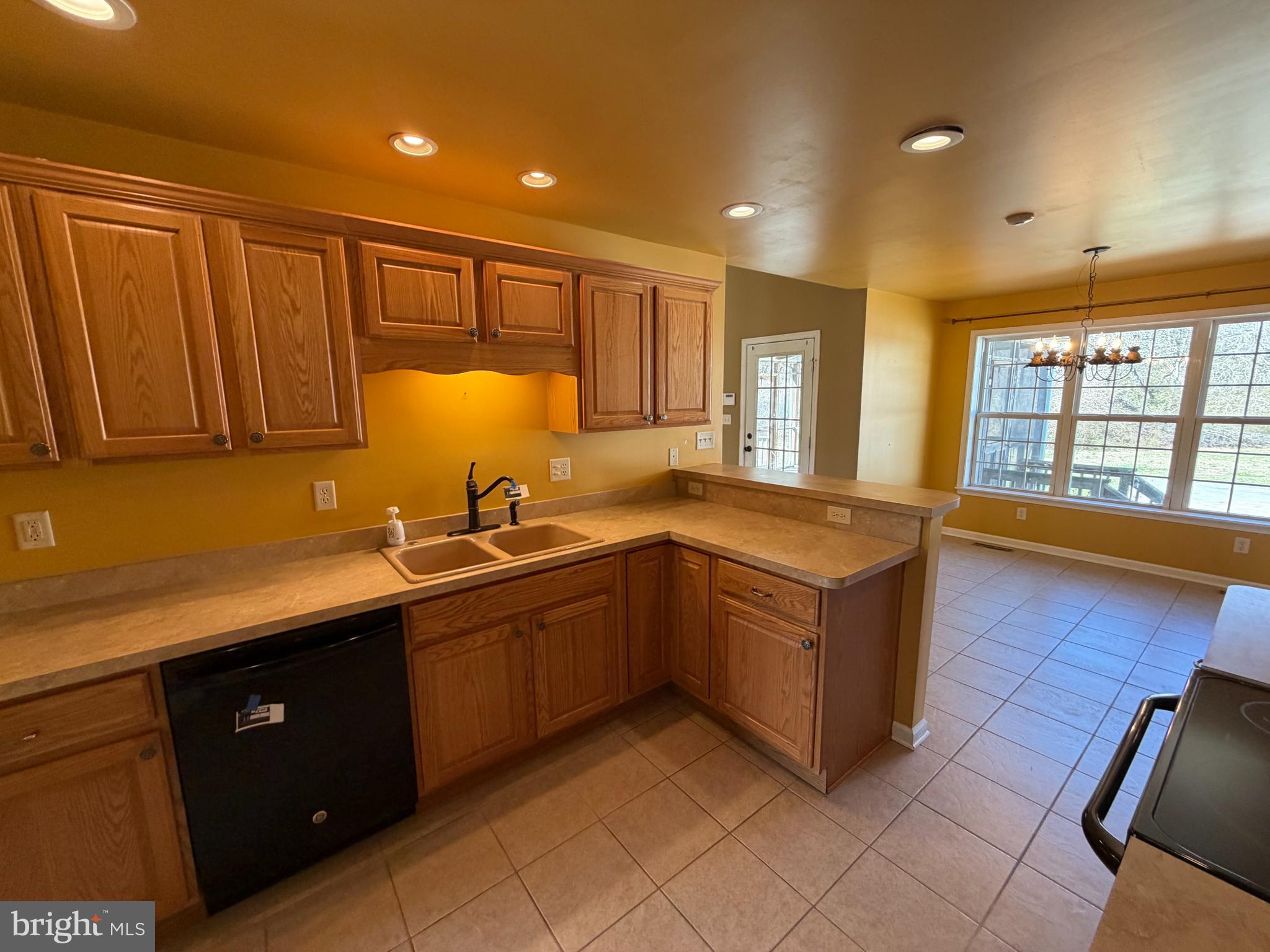 8617 Portsville Road Laurel, DE 19956 - Photo 31 of 47 a kitchen with stainless steel appliances granite countertop a sink and dishwasher wooden cabinets with a large window