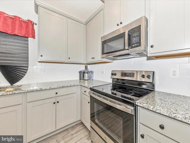 a kitchen with granite countertop cabinets stainless steel appliances and wooden floor