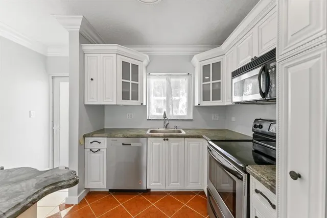 a kitchen with granite countertop a sink stove and microwave