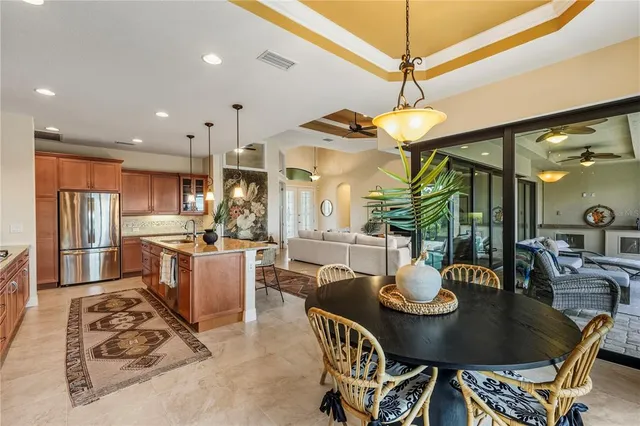 a kitchen with stainless steel appliances kitchen island granite countertop a sink a refrigerator a stove a dining table and chairs with wooden floor