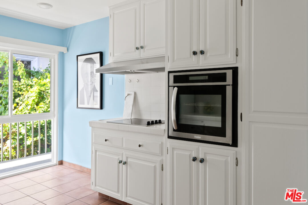 852 21st Street, Unit E Santa Monica, CA 90403 - Photo 7 of 20 a kitchen with white cabinets and a stove with wooden floor