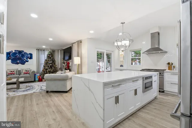 a large white kitchen with stainless steel appliances granite countertop a stove and a wooden floors
