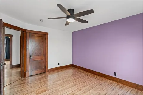 an empty room with wooden floor and a ceiling fan