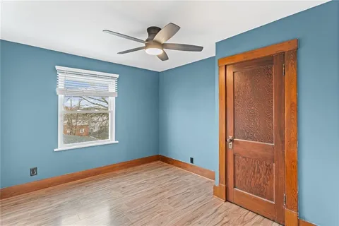 a view of empty room with wooden floor and ceiling fan