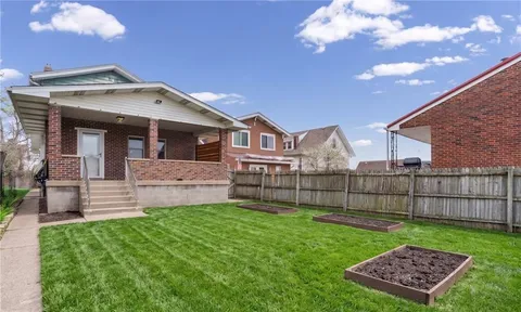 a view of a house with a big yard and large tree