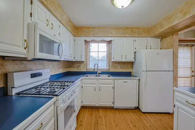 a kitchen with a refrigerator a stove a sink cabinets and wooden floor