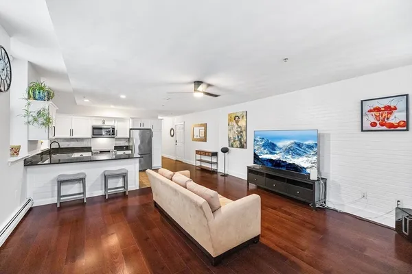 a living room with stainless steel appliances furniture and a kitchen view