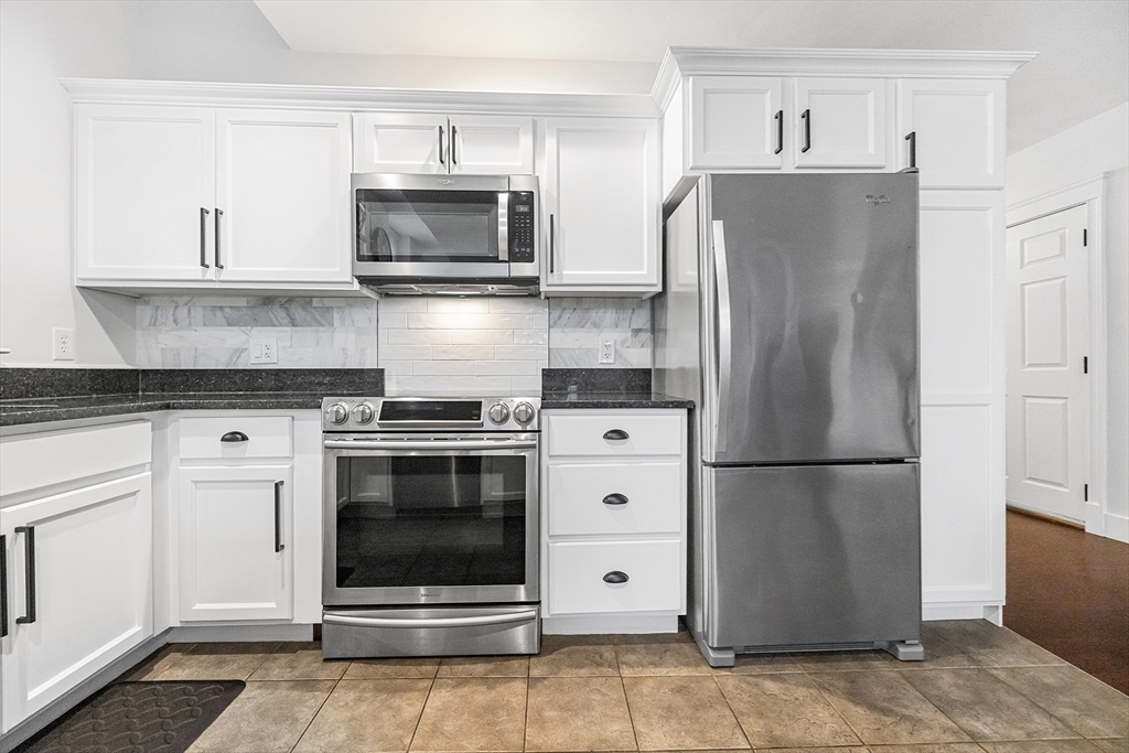 52-58 Washington Street, Unit BC Haverhill, MA 01832 - Photo 4 of 23 a kitchen with stainless steel appliances a refrigerator stove and microwave